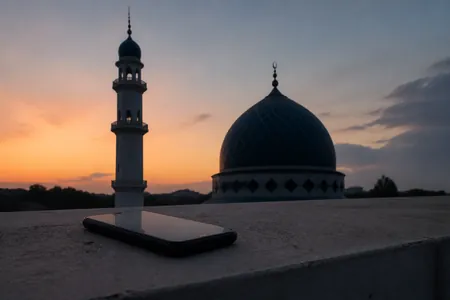 Menara dan kubah masjid ketika subuh, dengan telefon pintar skrin mati di hadapan